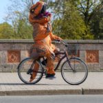 unrecognizable performer in costume of dinosaur riding bicycle