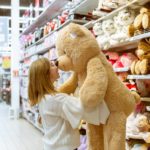 woman carrying bear plush toy inside store