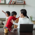 young ethnic woman trying to work at home with active children