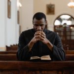a priest in black vestment praying