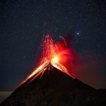 volcano erupting at night under starry sky