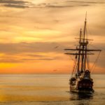 a pirate ship sailing on sea during golden hour