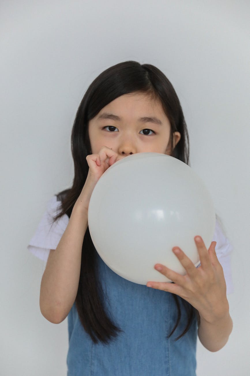 cute ethnic child inflating white balloon in studio