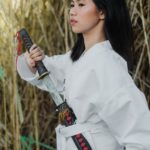 woman in white long sleeve clothing holding a sword