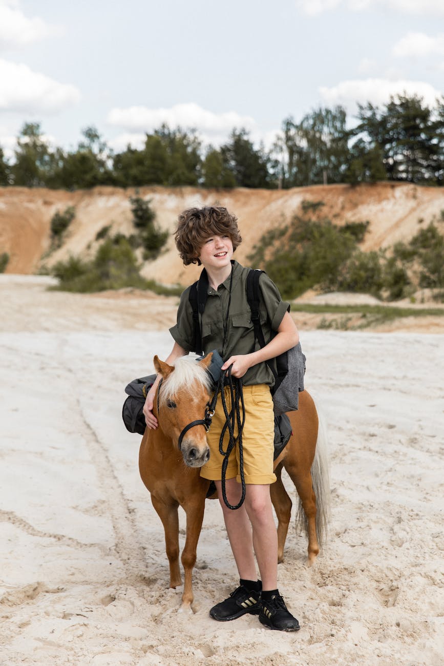 portrait of a boy with a mule standing on sand